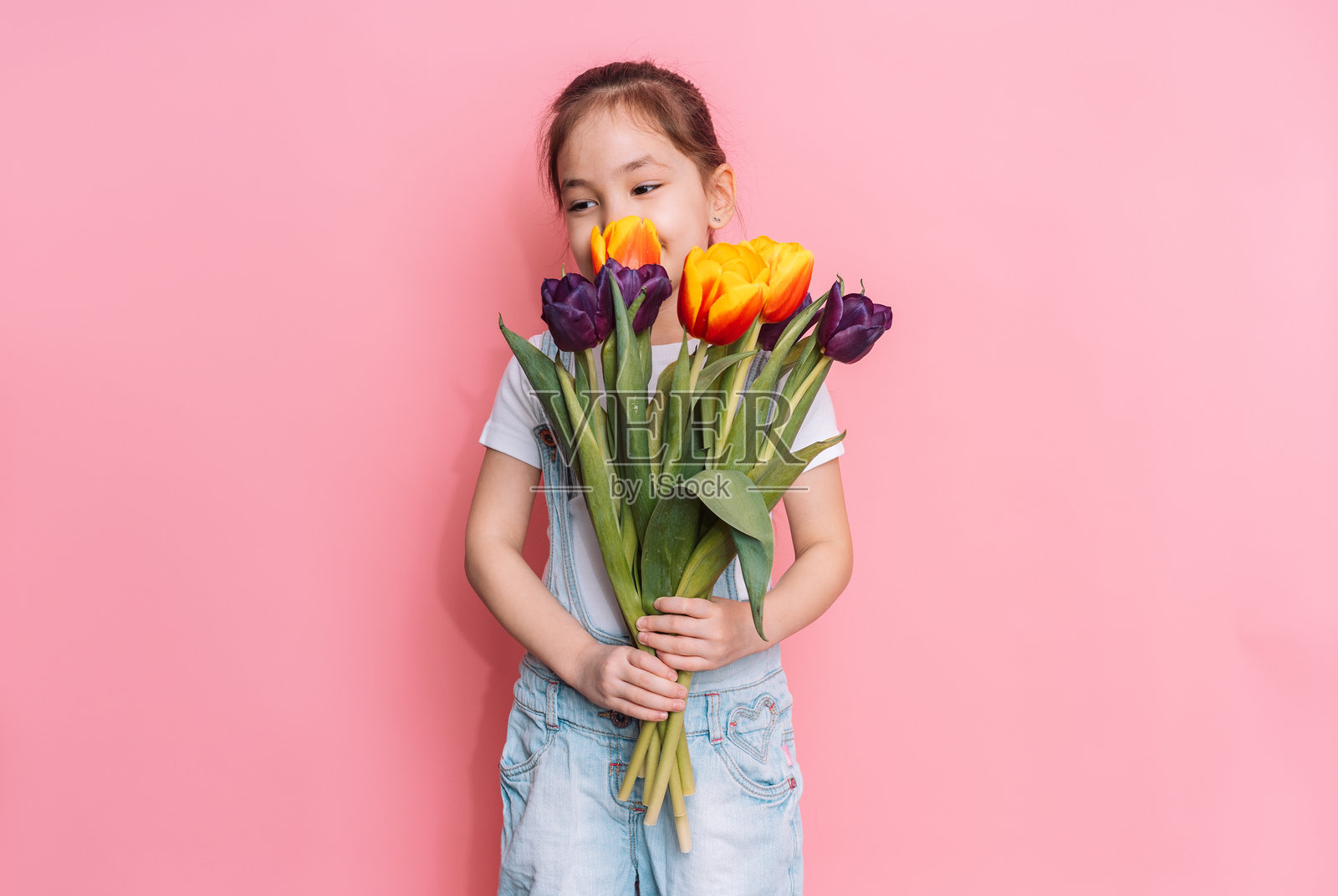 孩子在粉色背景前手捧一束郁金香照片摄影图片