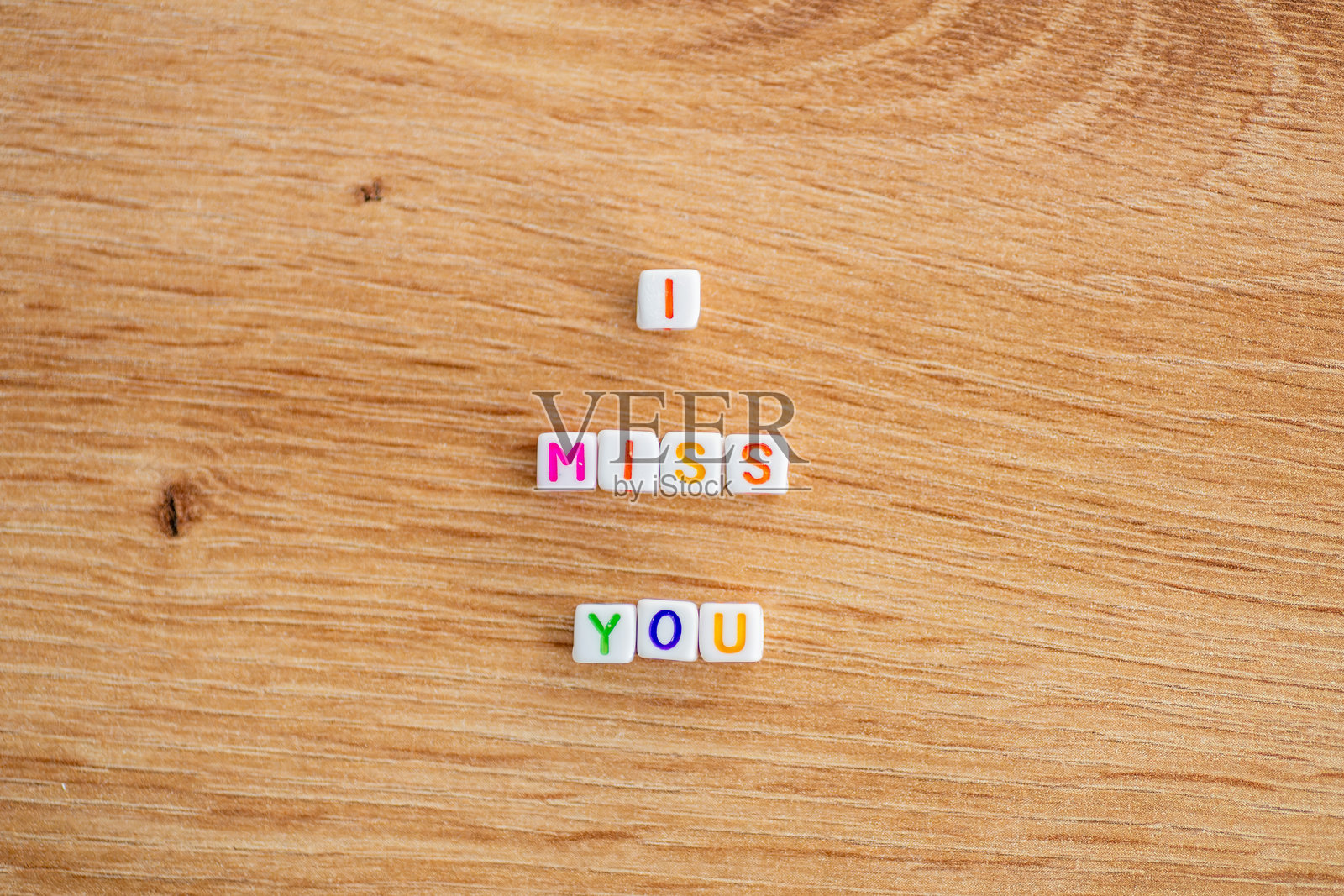 五彩字母积木拼出“我想你”字样，放在木头上照片摄影图片