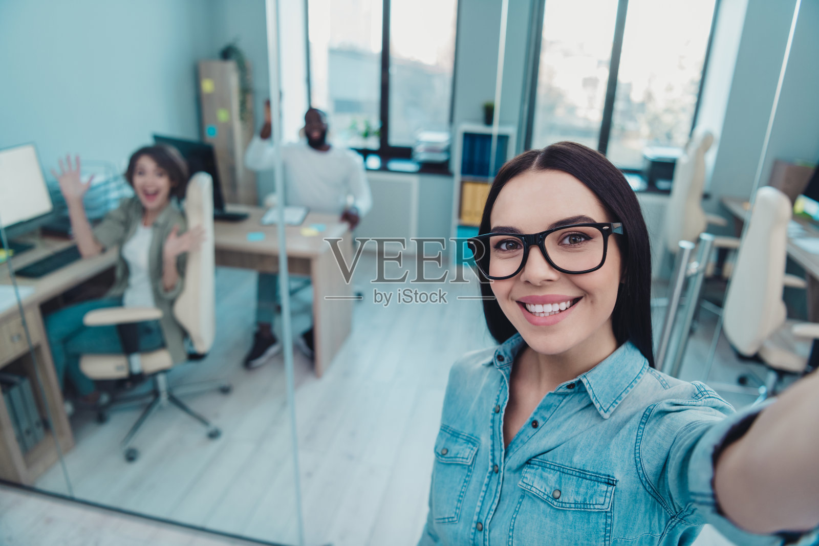 自信聪明的女士在工作空间与朋友自拍并打招呼，进行职业培训和学习博客。照片摄影图片