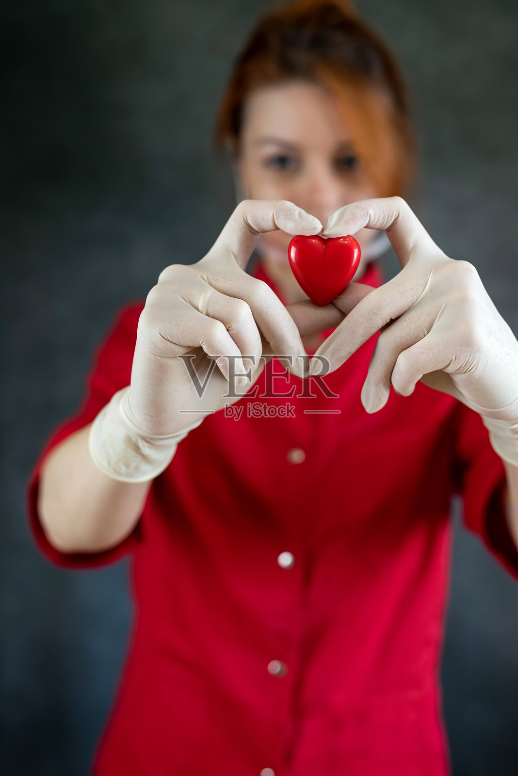 漂亮的白人女性医生手持红色心脏，背景为白色。照片摄影图片