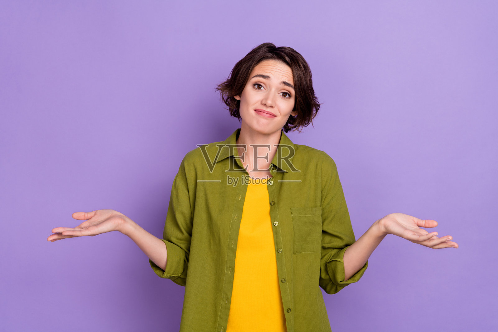 年轻女士在紫色背景下耸肩，情绪低落，显得无助和内疚。照片摄影图片