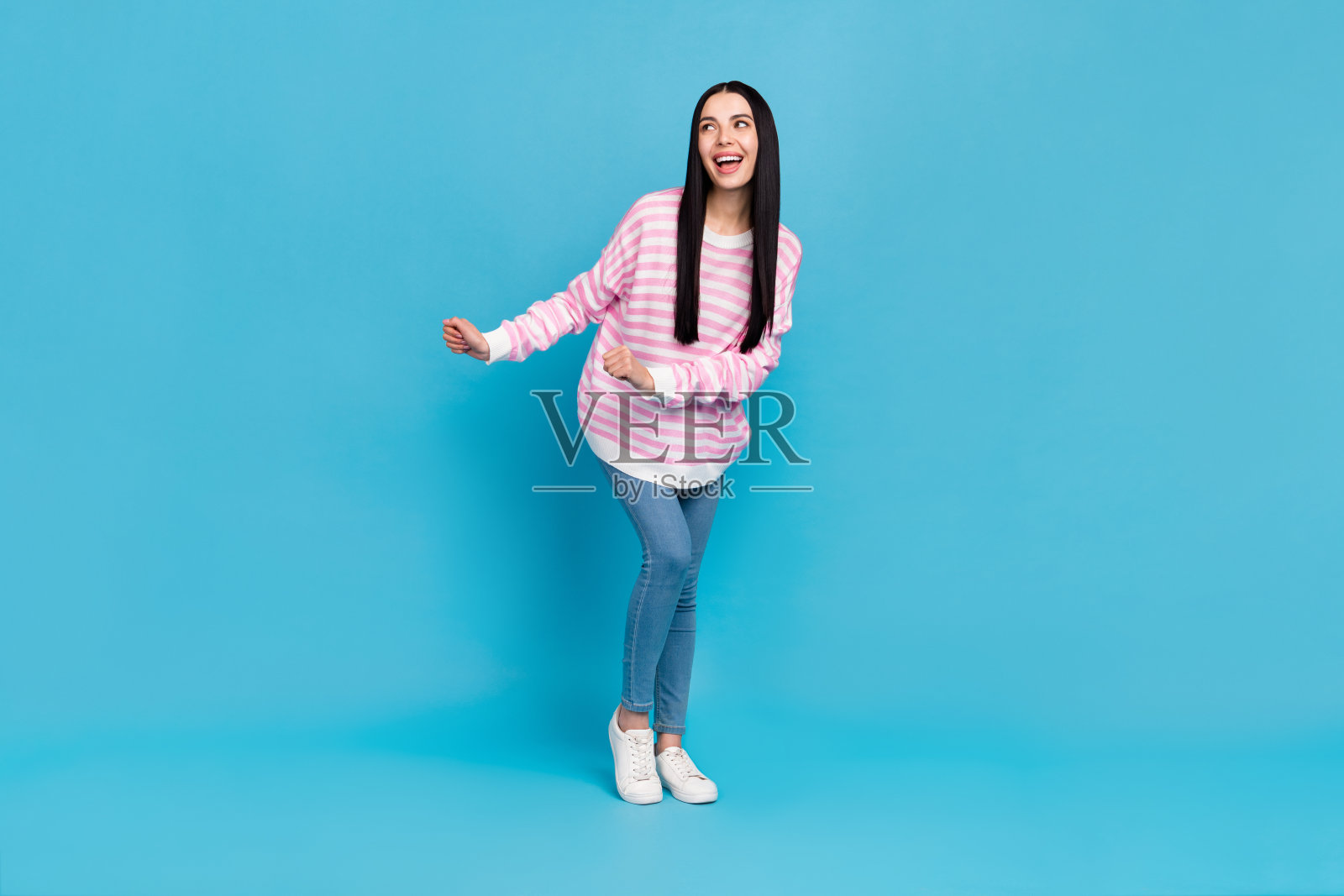 年轻漂亮的女性在蓝色背景下享受舞蹈，放松自在，周围空旷。照片摄影图片