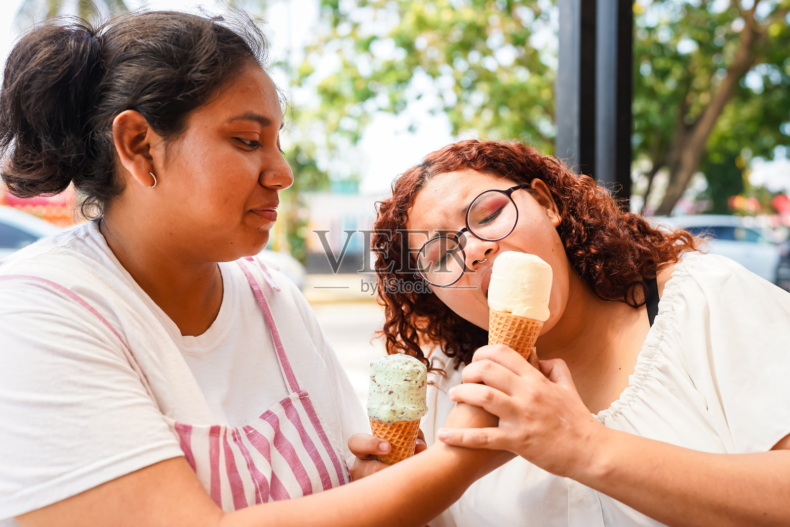 两位拉丁裔女性在户外一起享受冰淇淋甜筒照片摄影图片