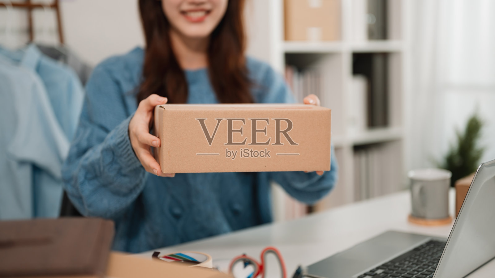 一位快乐的企业家特写展示一个包裹，体现了履行订单的兴奋、客户服务、可靠性以及经营中小企业的个人关怀。照片摄影图片