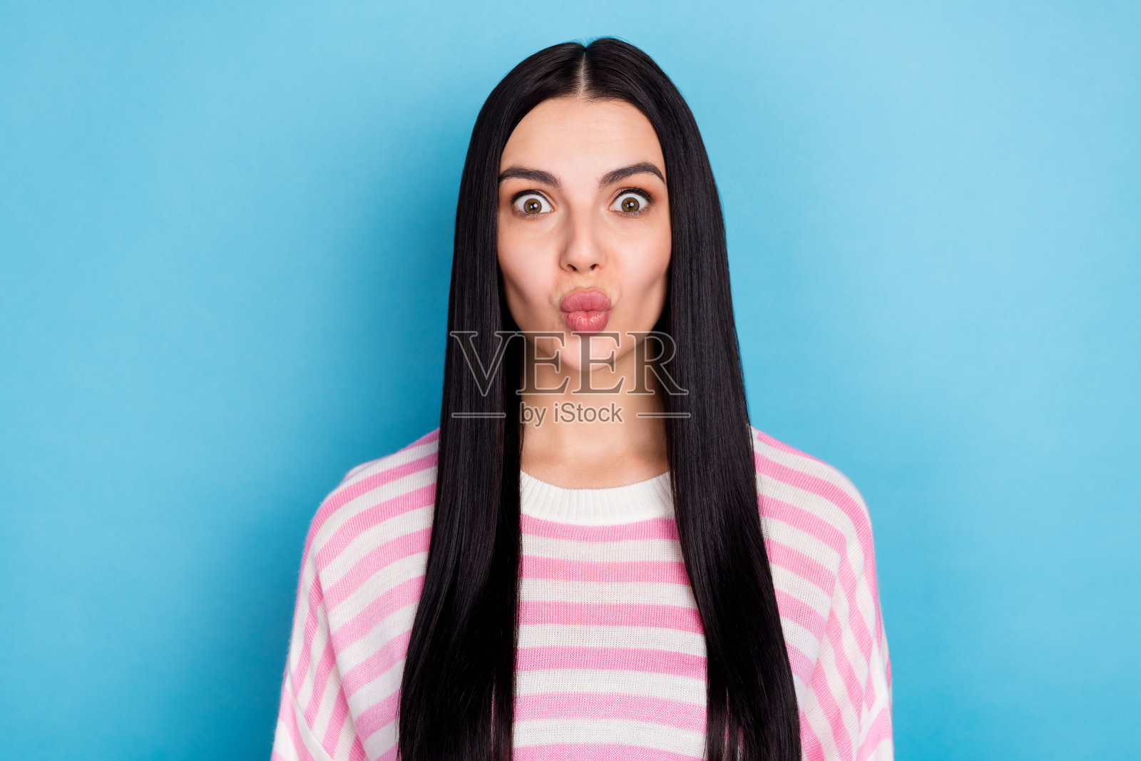 青春靓丽的女性撅嘴送空气吻，美容摄影，背景为蓝色。照片摄影图片