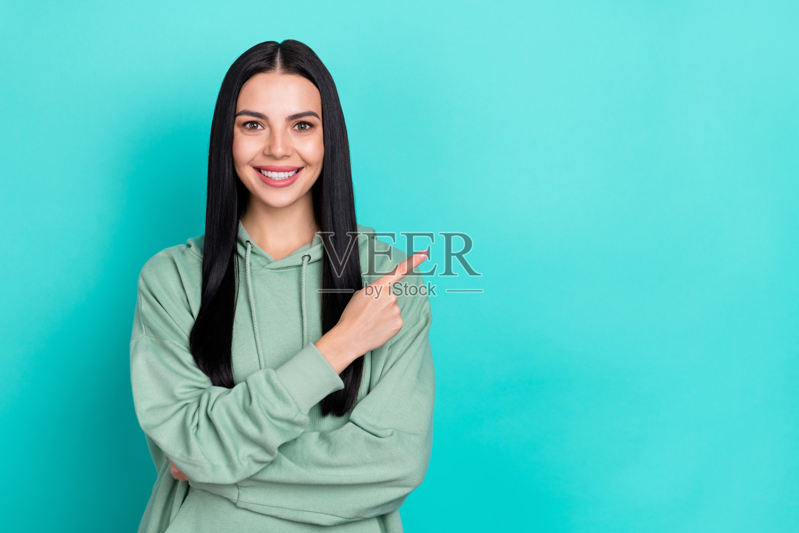 穿着绿色运动服的甜美千禧一代黑人女士，手指指向促销，背景为青绿色。照片摄影图片