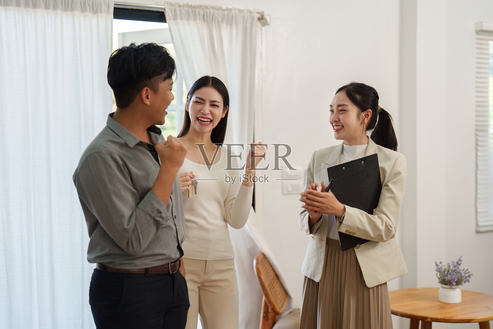 庆祝拥有房屋。一对快乐的夫妇在完成购房后与他们的房地产经纪人一起庆祝。照片摄影图片