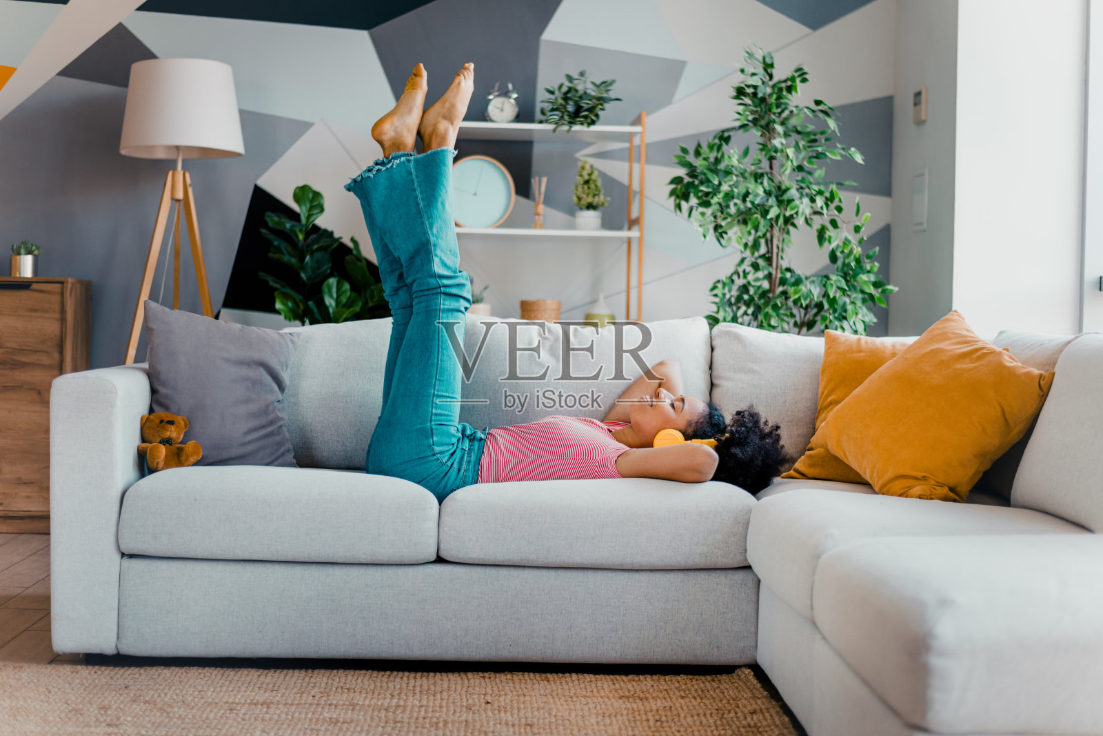 年轻女性在沙发上放松，双腿翘起，享受时光，感受时尚而充满活力的家居环境带来的舒适。照片摄影图片