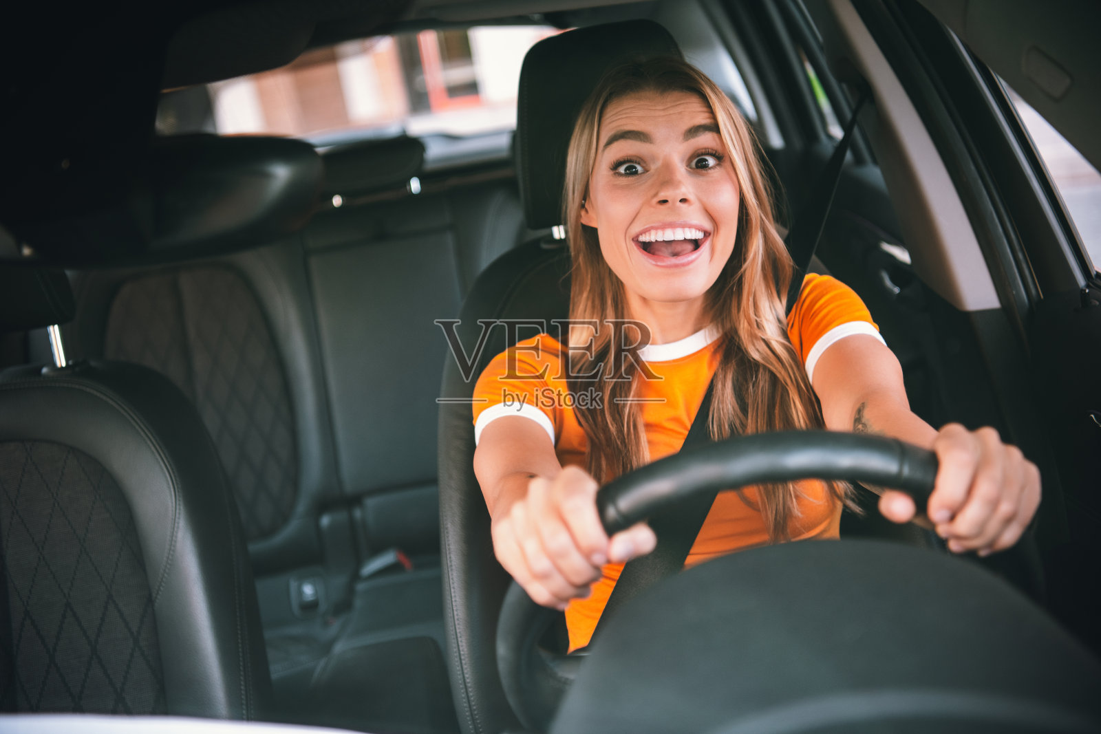 快乐的年轻女性在白天的城市环境中，面带愉悦表情享受汽车旅程照片摄影图片