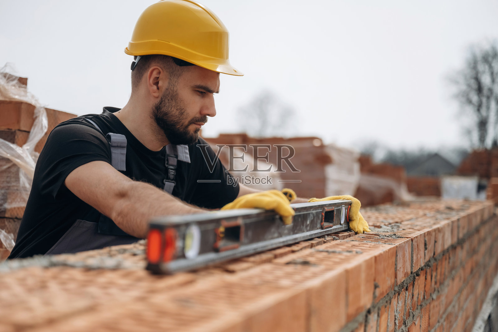 工人在户外用工具调整砖块的正确高度。照片摄影图片