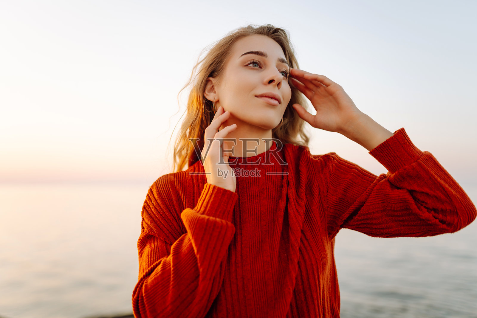 美丽的女人微笑着走在码头上，背景是海景。照片摄影图片