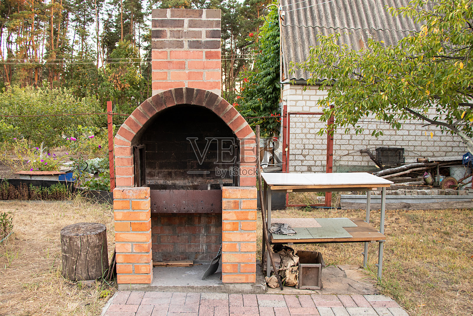 夏季小屋周围绿树成荫的砖砌烧烤架照片摄影图片