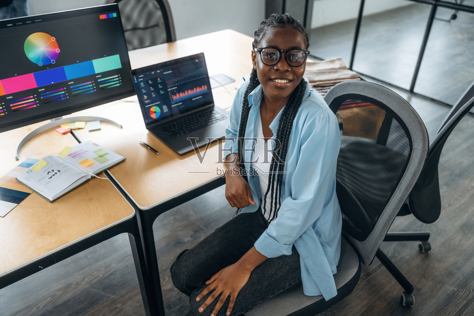 露齿而笑，坐着。设计师在办公室工作。照片摄影图片