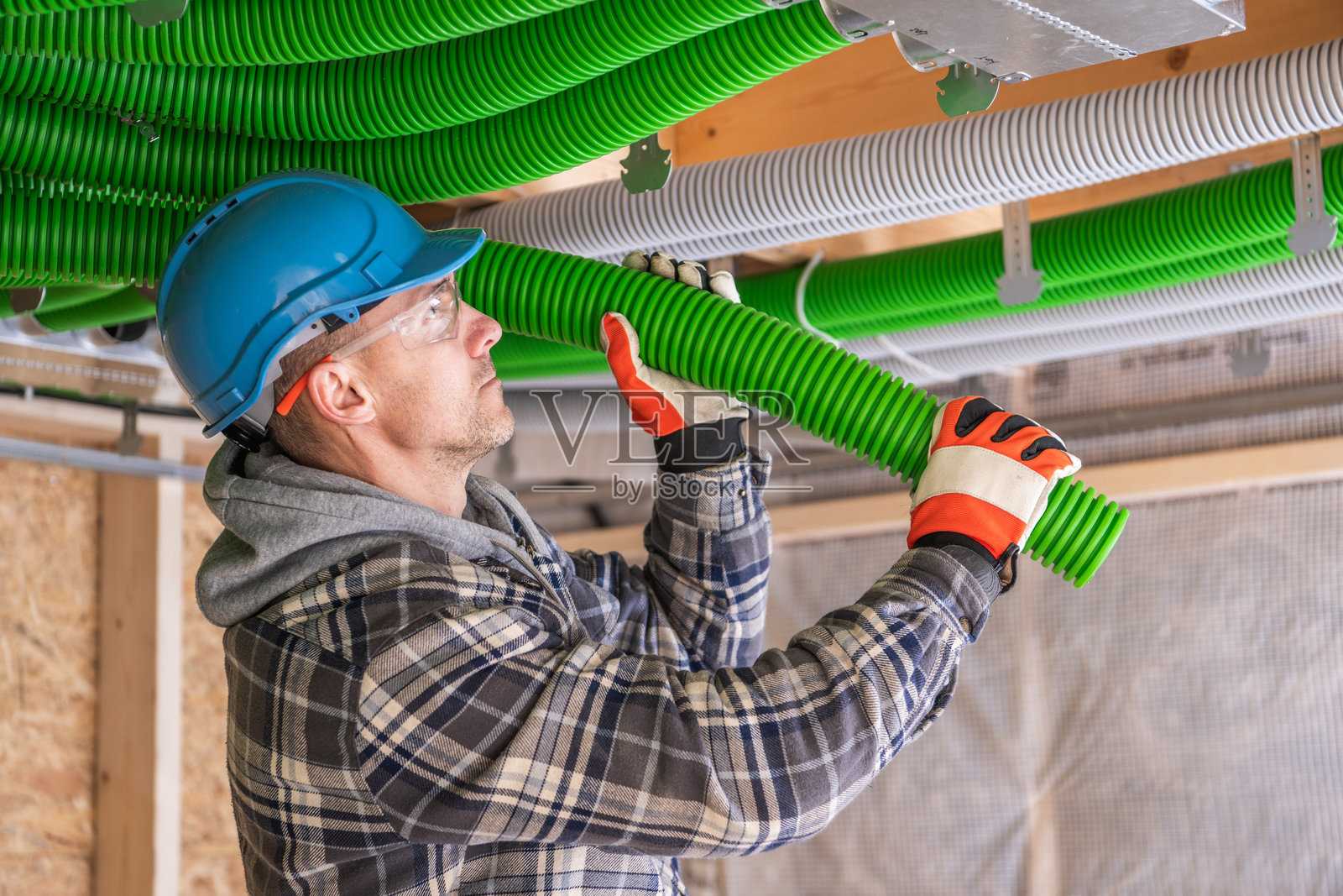 工人在建筑工地天花板区域安装绿色管道照片摄影图片
