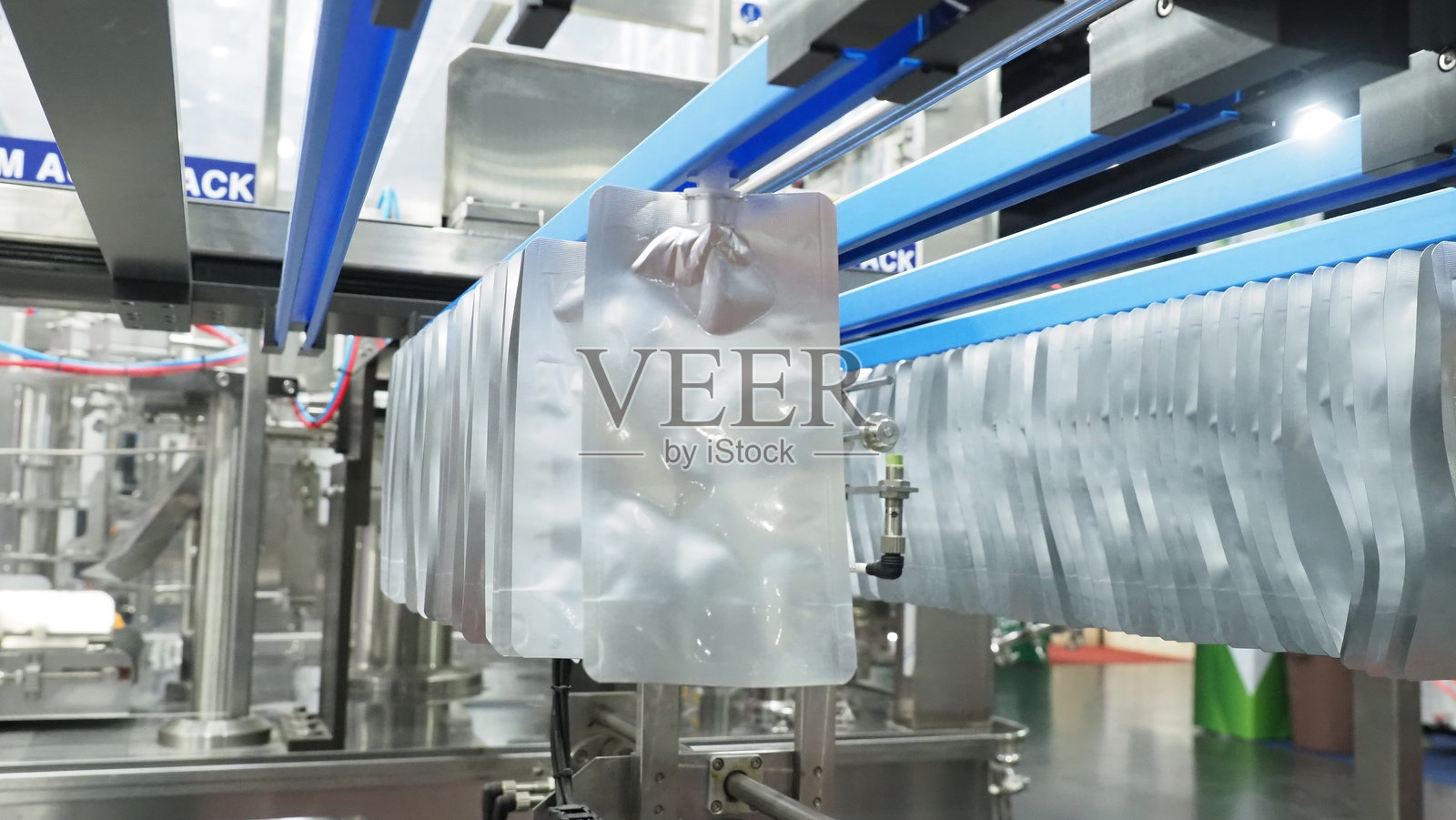 自动包装机在工业生产线上填充银色喷嘴袋。照片摄影图片