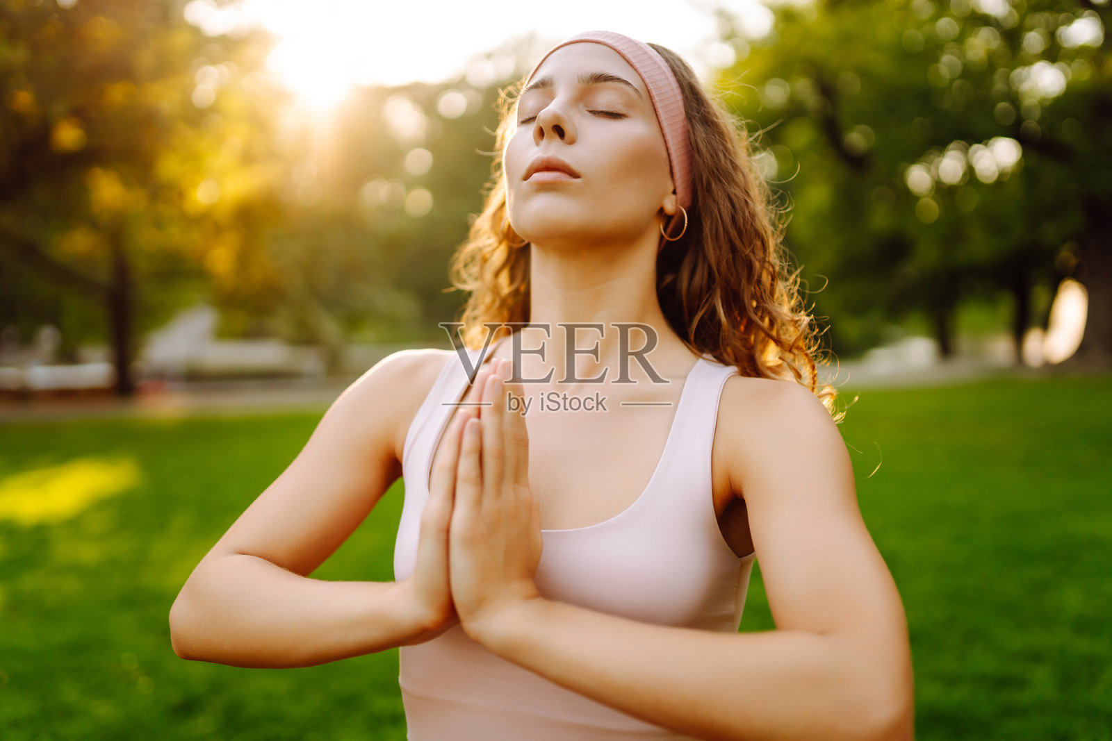 年轻女性在阳光明媚的公园里瑜伽垫上做运动。照片摄影图片