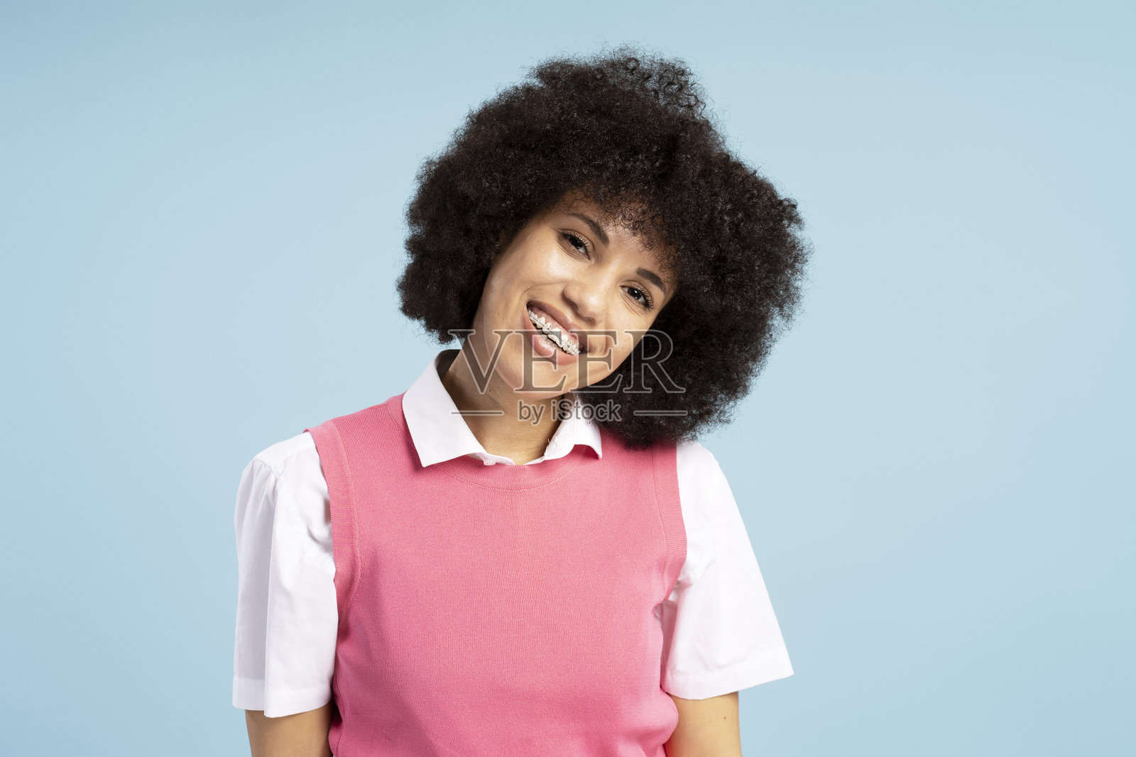 美丽、微笑的非裔美国女性，带着牙套，背景为蓝色。照片摄影图片