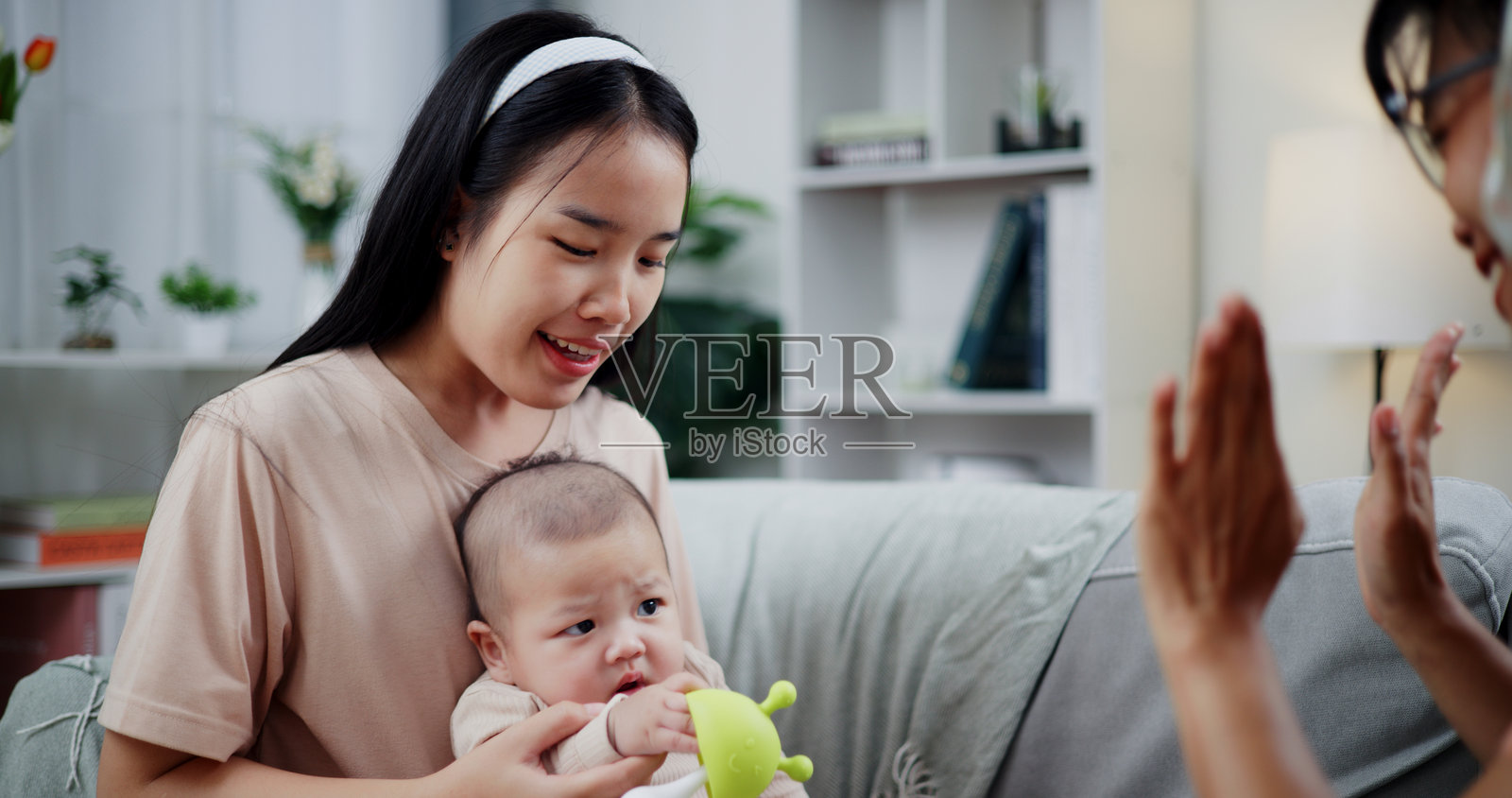 两位女性在家里的客厅沙发上快乐地和一个小男孩玩耍。照片摄影图片