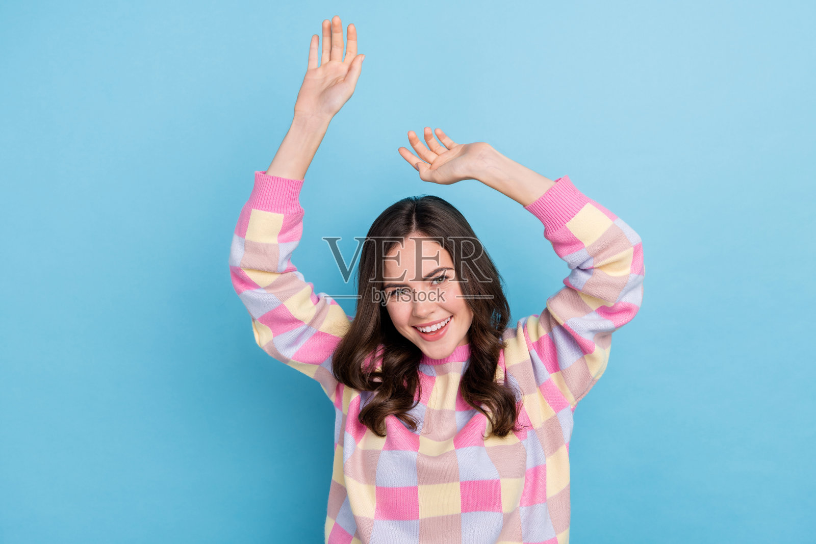 年轻可爱的女性在蓝色背景下无忧无虑地跳舞，心情愉快，享受聚会的氛围。照片摄影图片