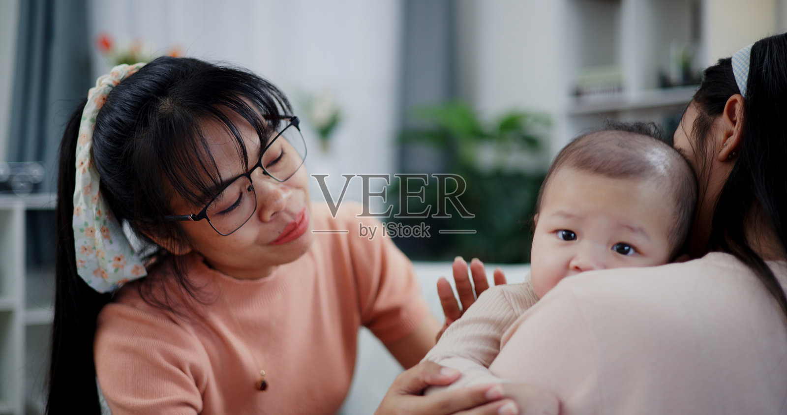 母亲和女儿在客厅里快乐地和小男孩玩耍。照片摄影图片