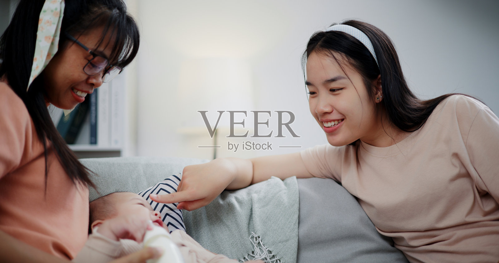 两位女性在家里的客厅沙发上快乐地和一个小男孩玩耍。照片摄影图片