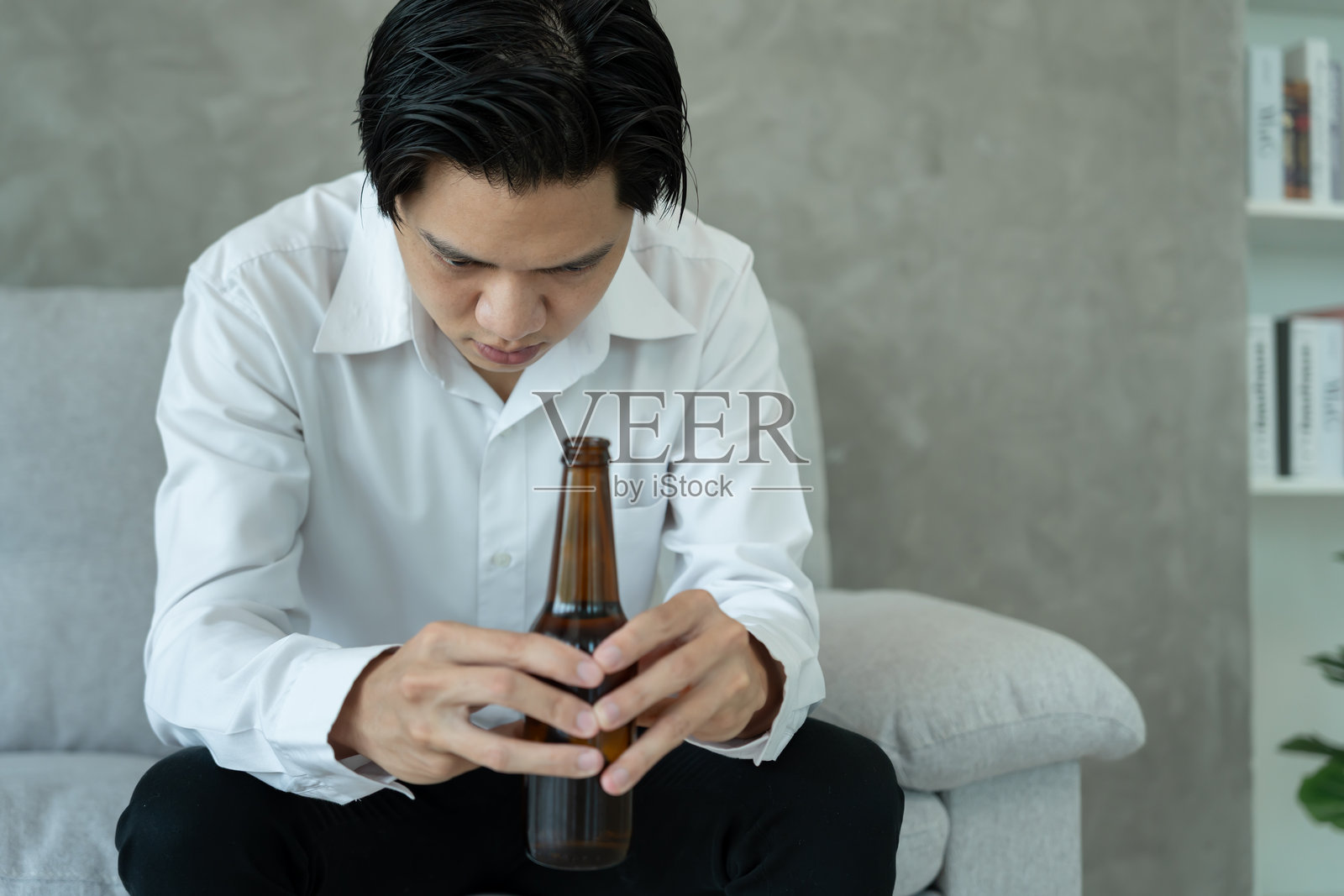 沮丧的年轻商人独自在家喝威士忌，感到痛苦，压力大，孤独，因酗酒而遭受生活和家庭问题的困扰。照片摄影图片