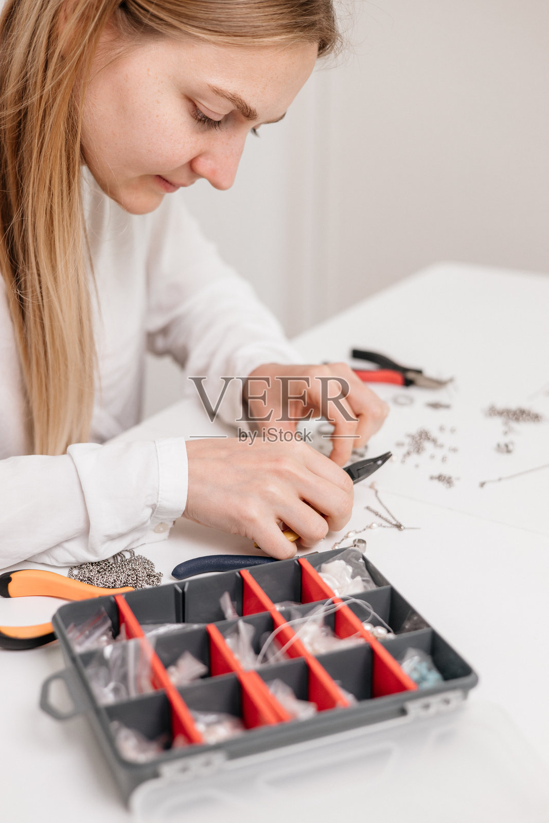 年轻女性在家中的工作台上用干花和工具制作DIY首饰照片摄影图片