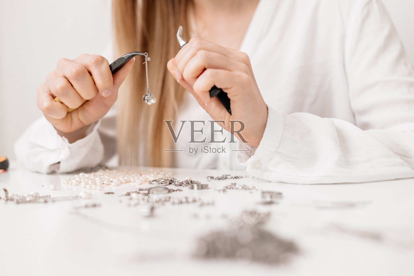 年轻女性在家中的工作台上用干花和工具制作DIY首饰照片摄影图片