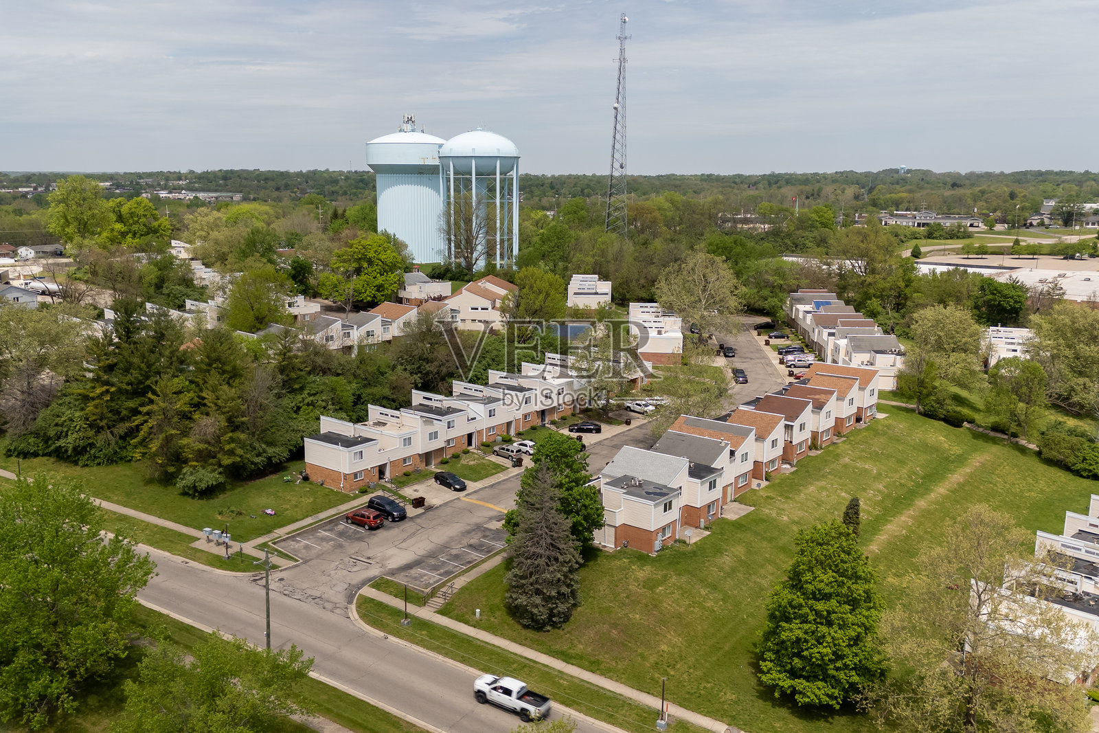 一座水塔高耸在郊区社区，周围环绕着房屋和树木。照片摄影图片