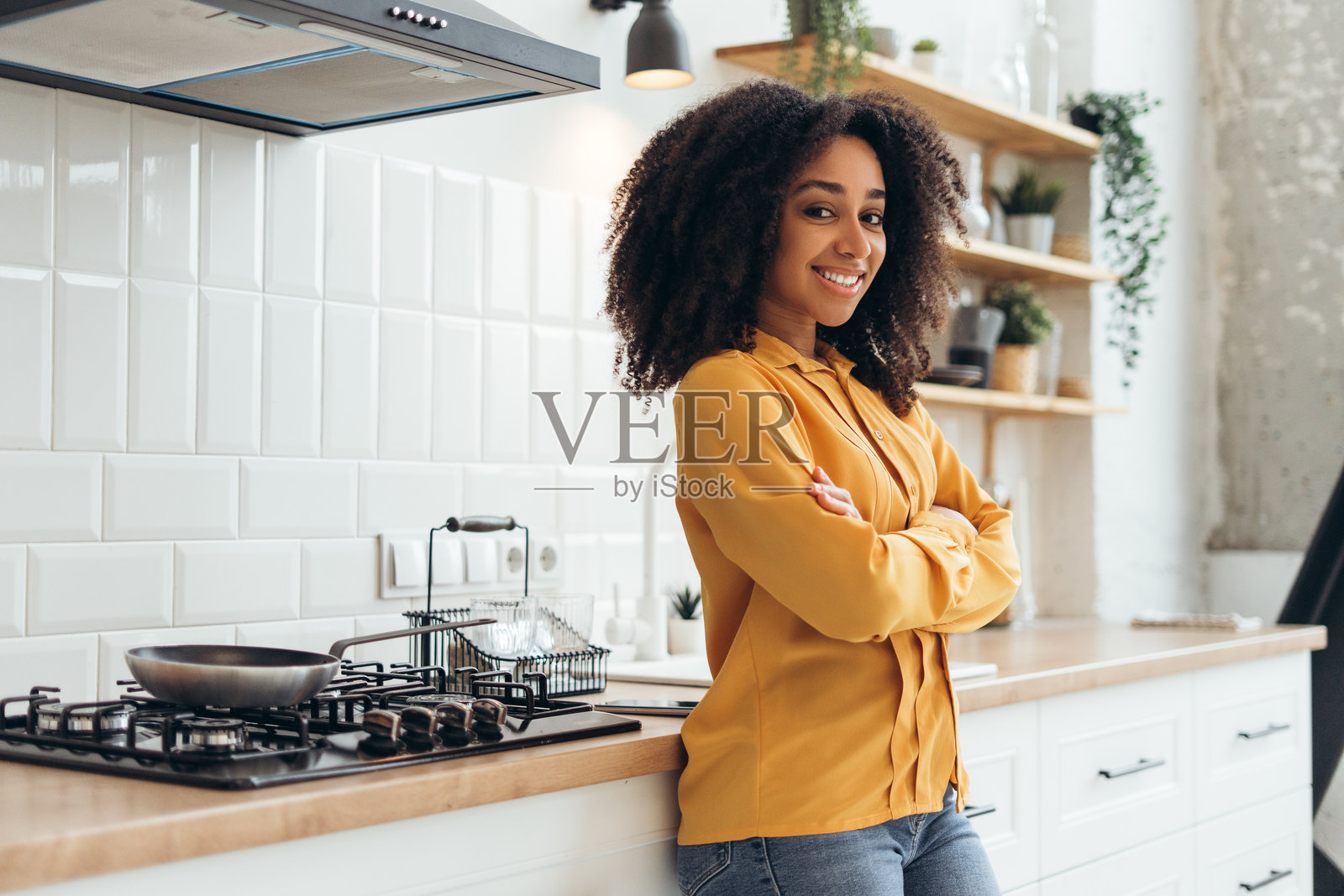 年轻女性微笑着，双臂交叉在现代厨房里照片摄影图片