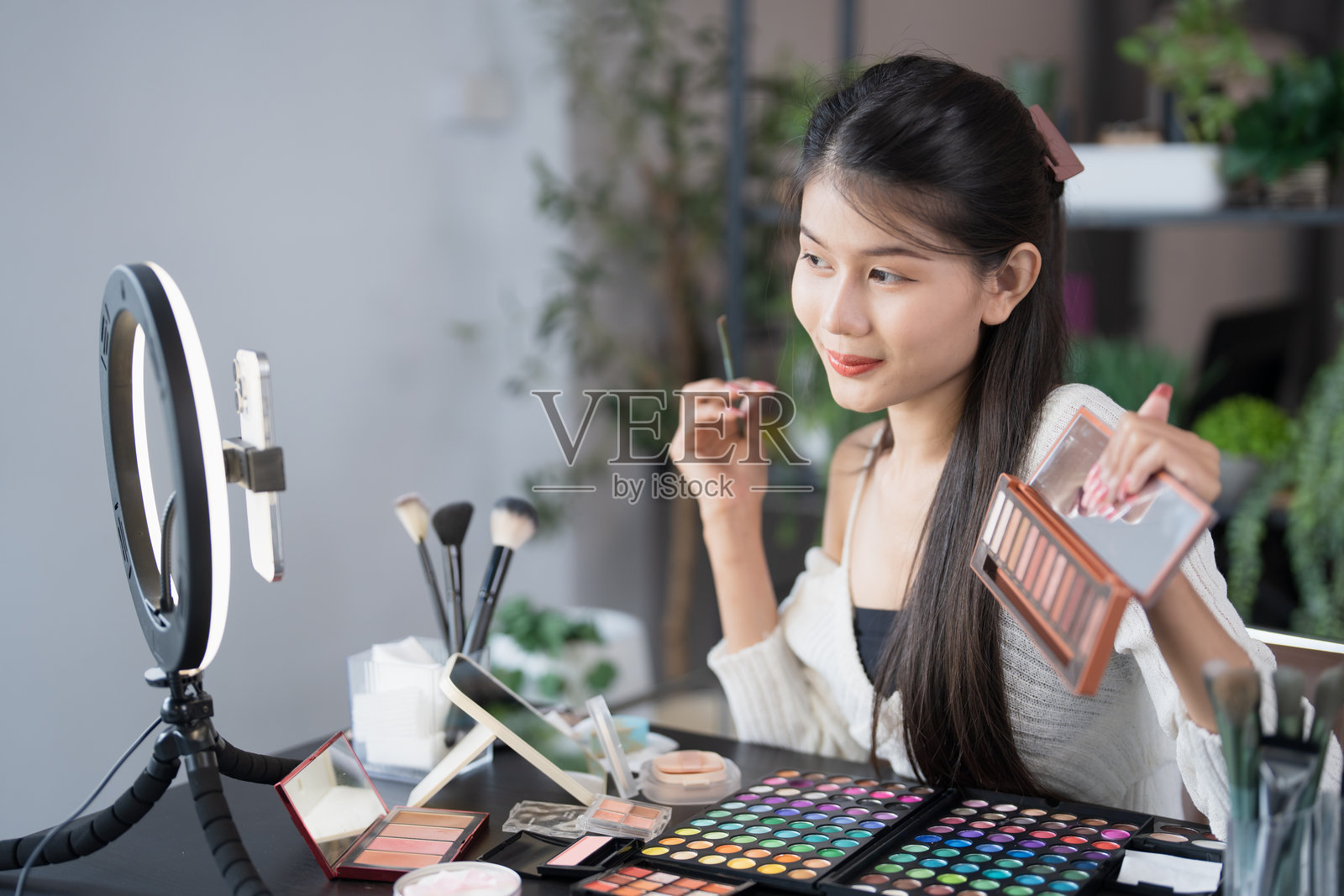 美容博主年轻亚洲女孩化妆师专业女性博主视频博主正在展示化妆品产品并录制视频，美容影响者亚洲女孩在线营销直播。照片摄影图片