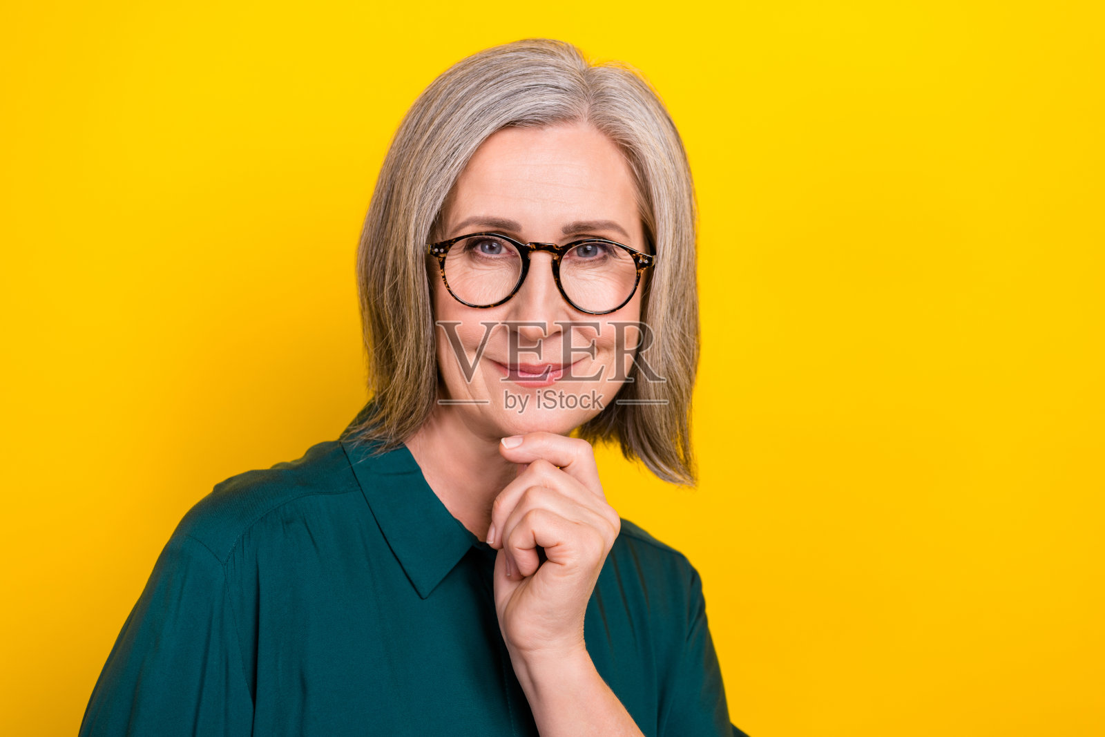 聪明积极的年长女性企业家手托下巴，空旷的空间，背景为黄色。照片摄影图片