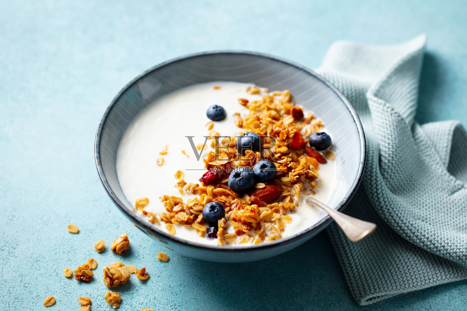 蓝莓酸奶碗中的脆 granola。蓝色背景。特写。照片摄影图片