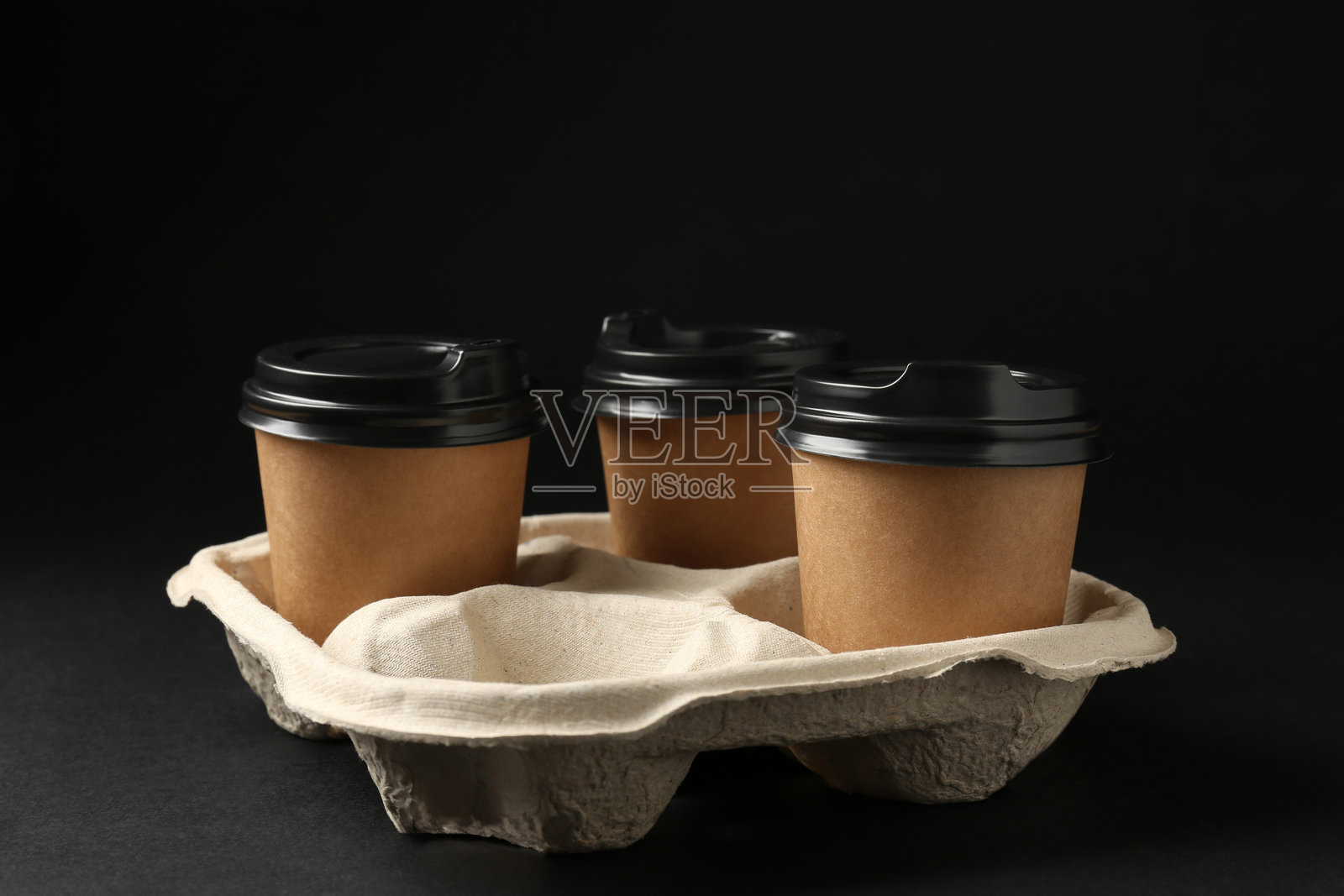 黑色背景上的纸质咖啡杯和纸板托架特写照片摄影图片