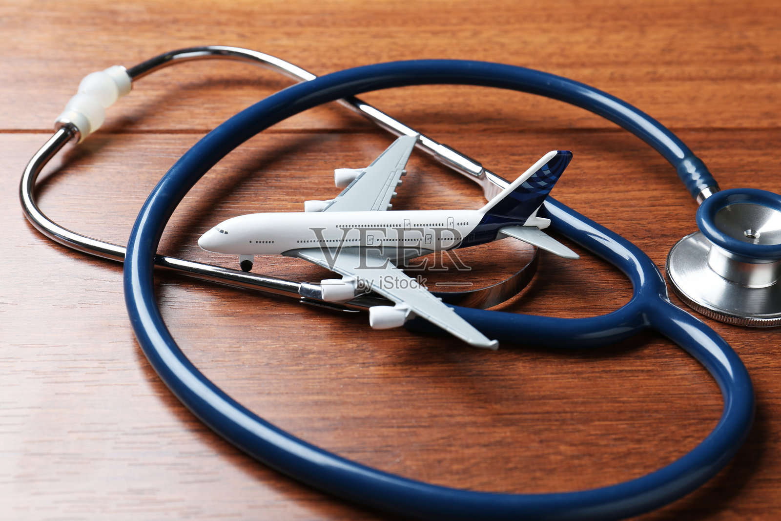 医疗旅游。木质背景上的听诊器和飞机模型，特写。照片摄影图片