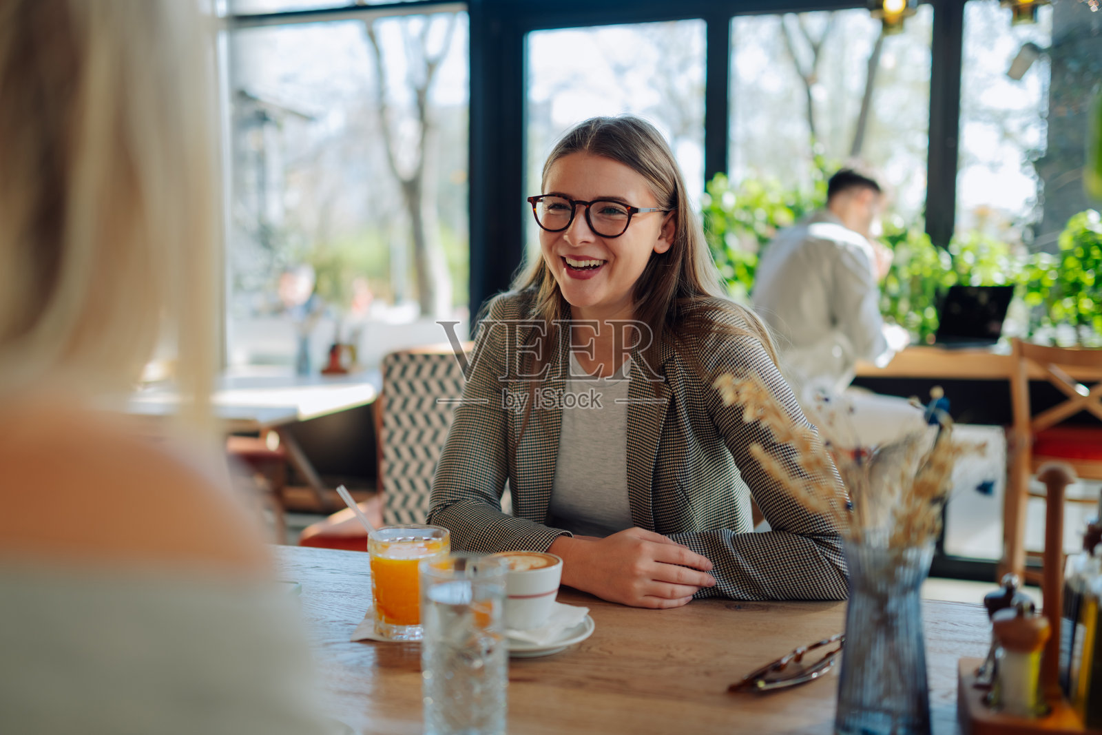 年轻女商人在咖啡馆与朋友交谈时笑得很开心照片摄影图片
