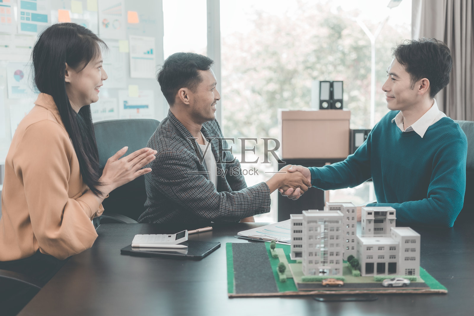 房地产商人与客户握手达成出售房屋的协议，并签署合同文件。照片摄影图片