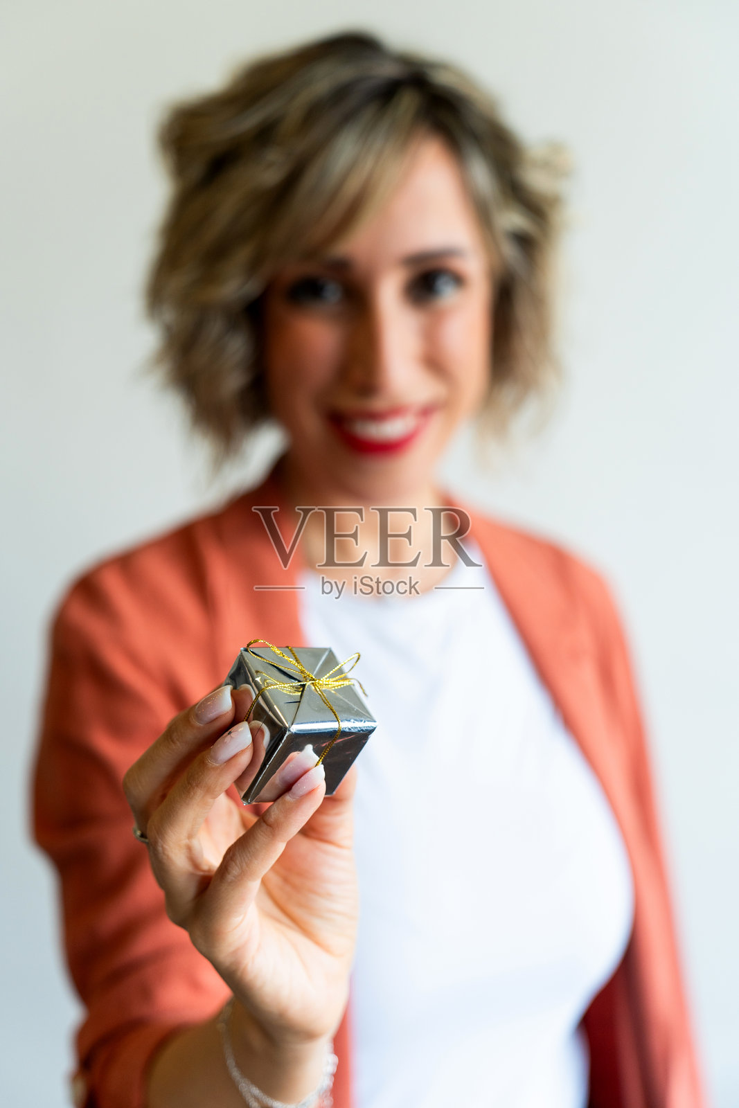 微笑的女性手持一个小银色礼品盒照片摄影图片
