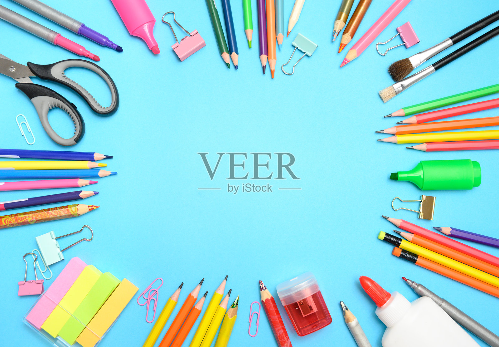 蓝色背景上的多彩文具，中央留有空白空间。照片摄影图片