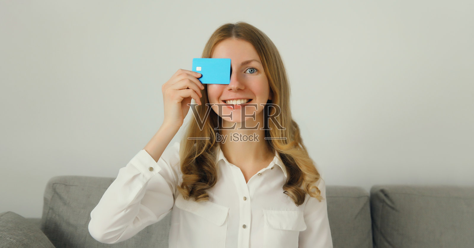 快乐微笑的年轻女性手持塑料信用卡，愉快的女孩在家中。照片摄影图片