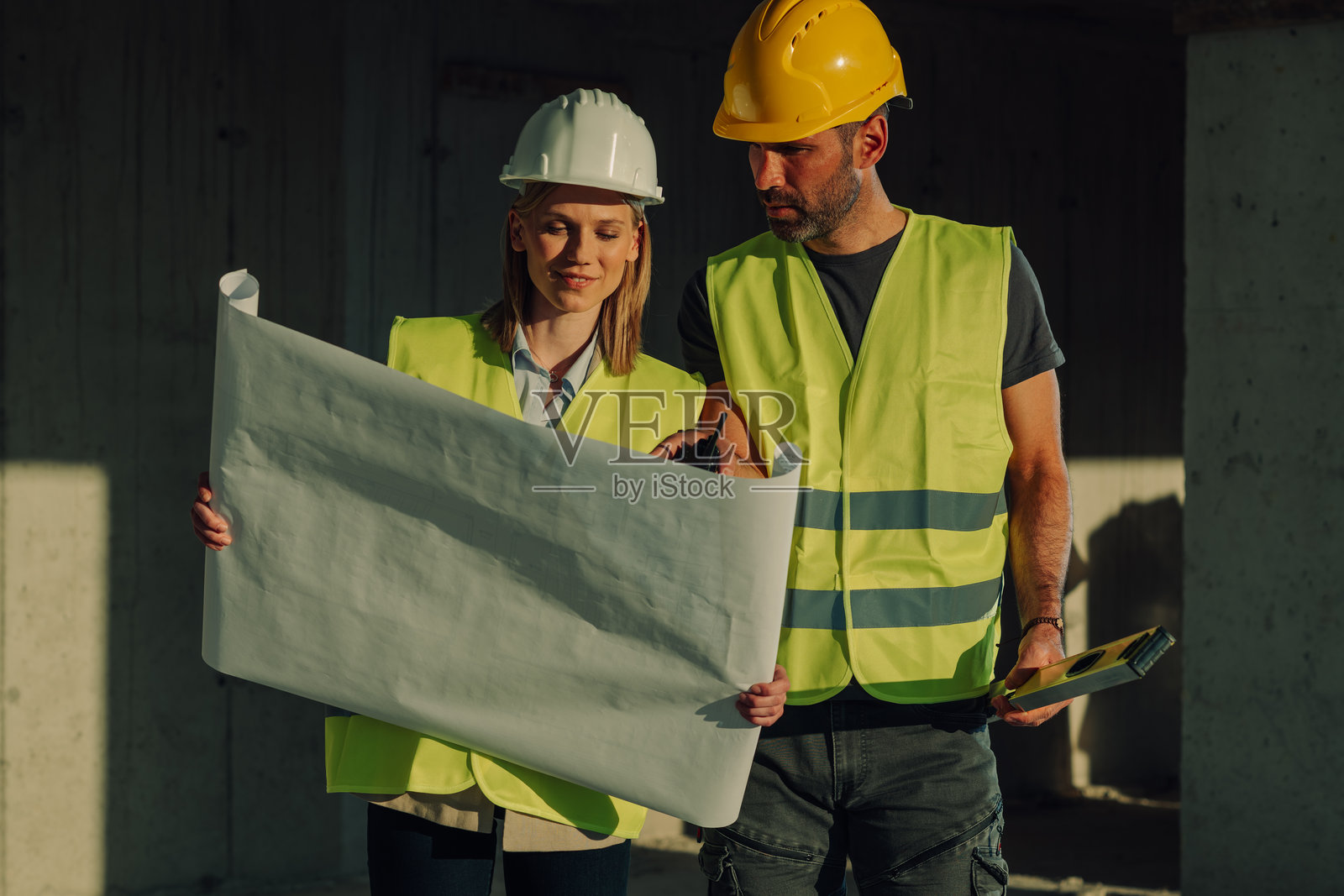 建筑工人在工地上检查蓝图照片摄影图片