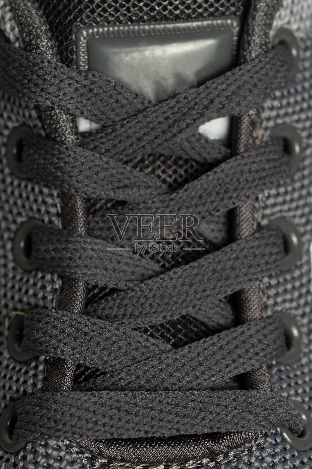 灰色运动鞋的特写，鞋带在灰色背景上。照片摄影图片