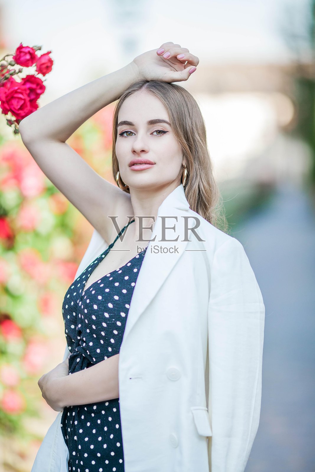 年轻美丽的女人在盛开玫瑰的欧洲城市中漫步。照片摄影图片