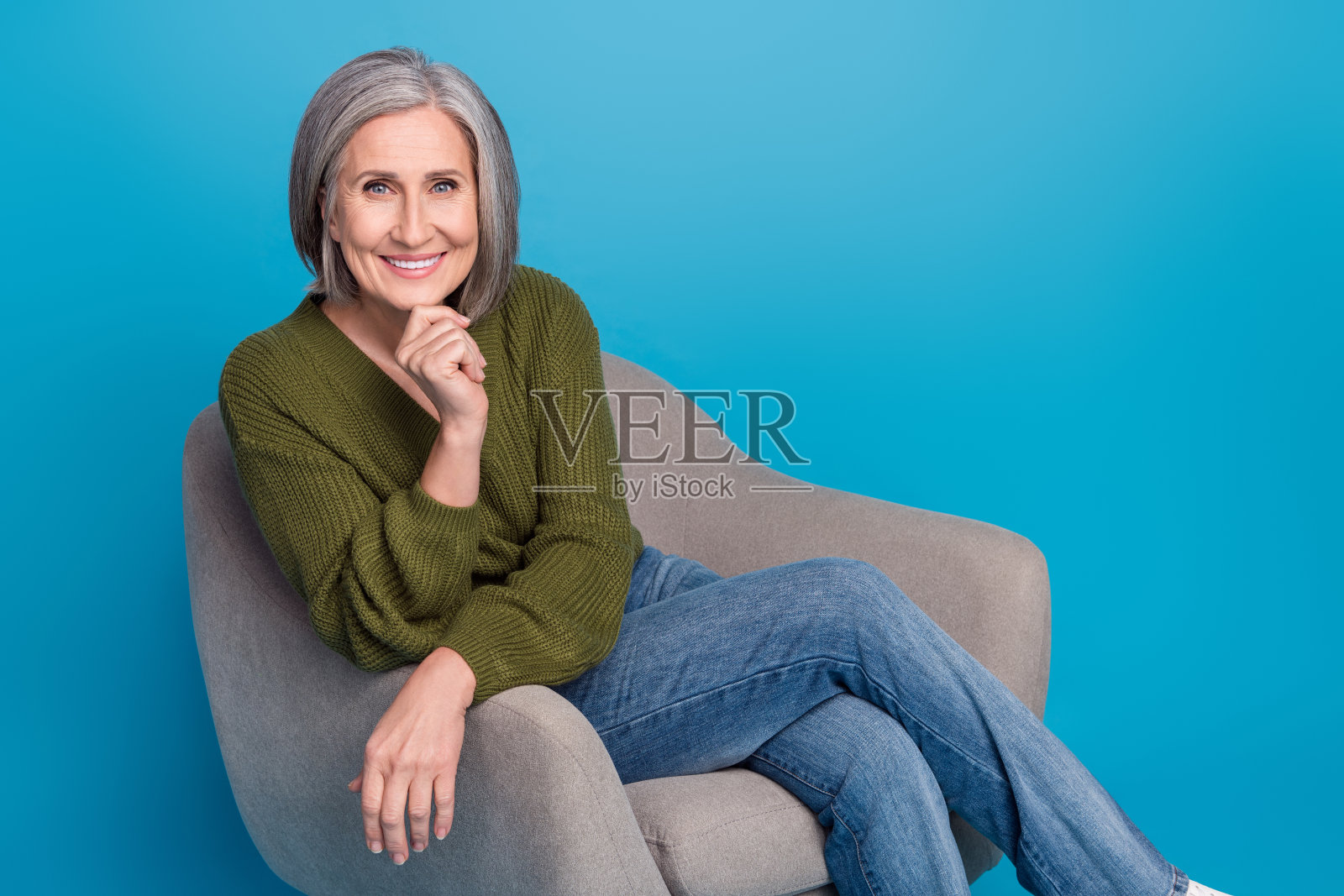 迷人的医生肖像，经验丰富的女性触摸下巴，心理治疗师广告，孤立在蓝色背景上。照片摄影图片