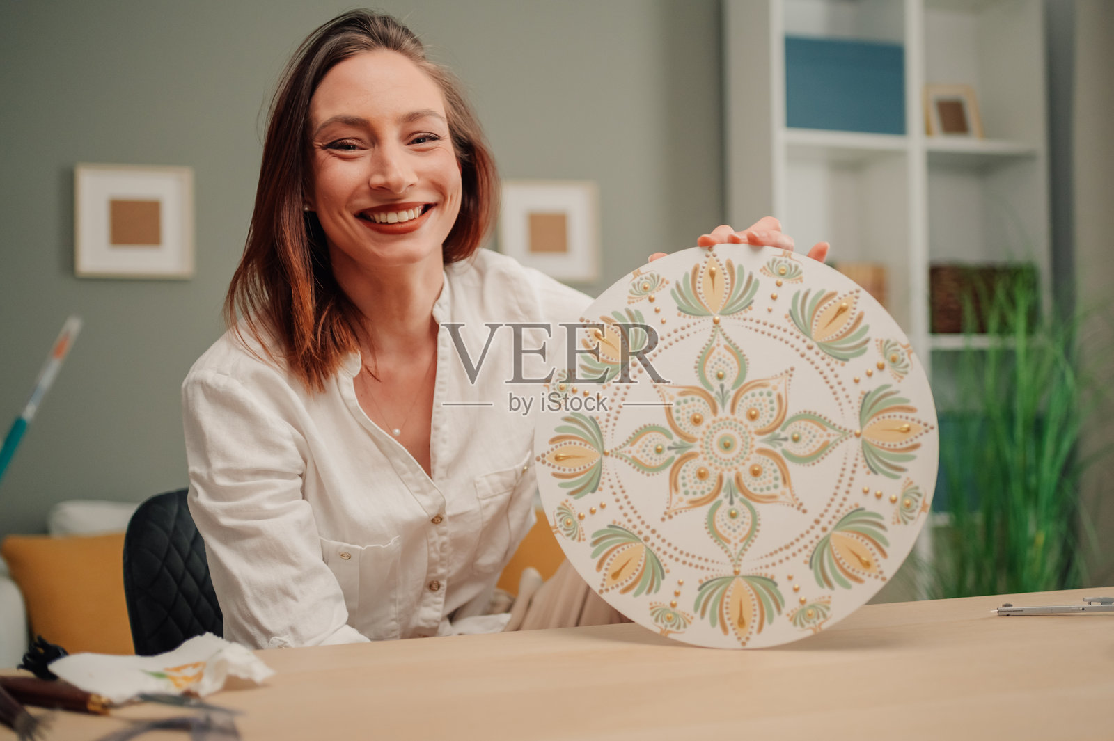 年轻女性微笑着向镜头展示她的点状曼荼罗艺术作品照片摄影图片