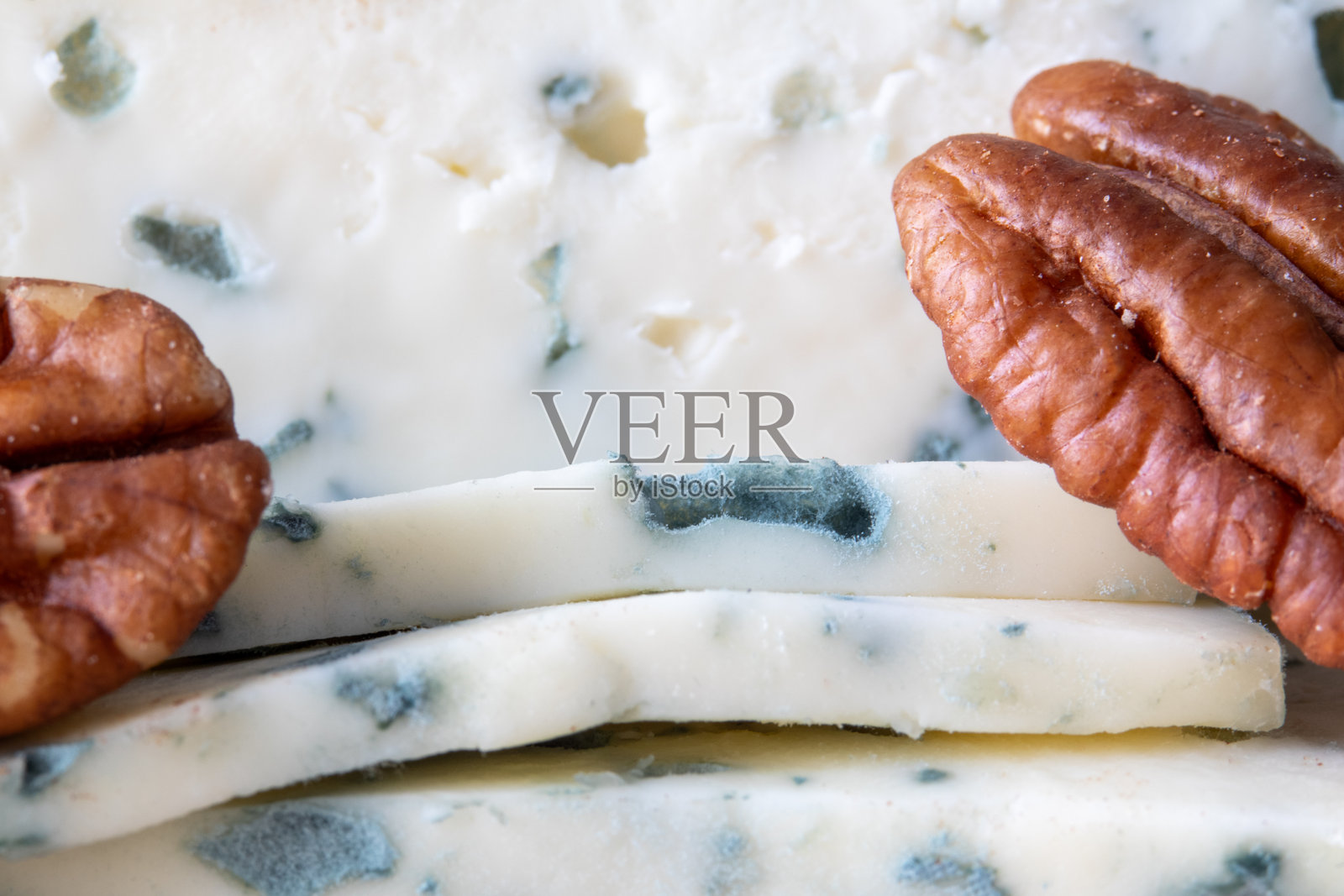 带有可见霉斑的蓝纹奶酪切片和完整的胡桃，背景为中性色调照片摄影图片