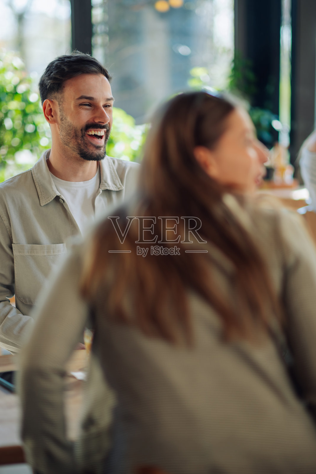 年轻男子在餐厅与朋友们欢笑照片摄影图片