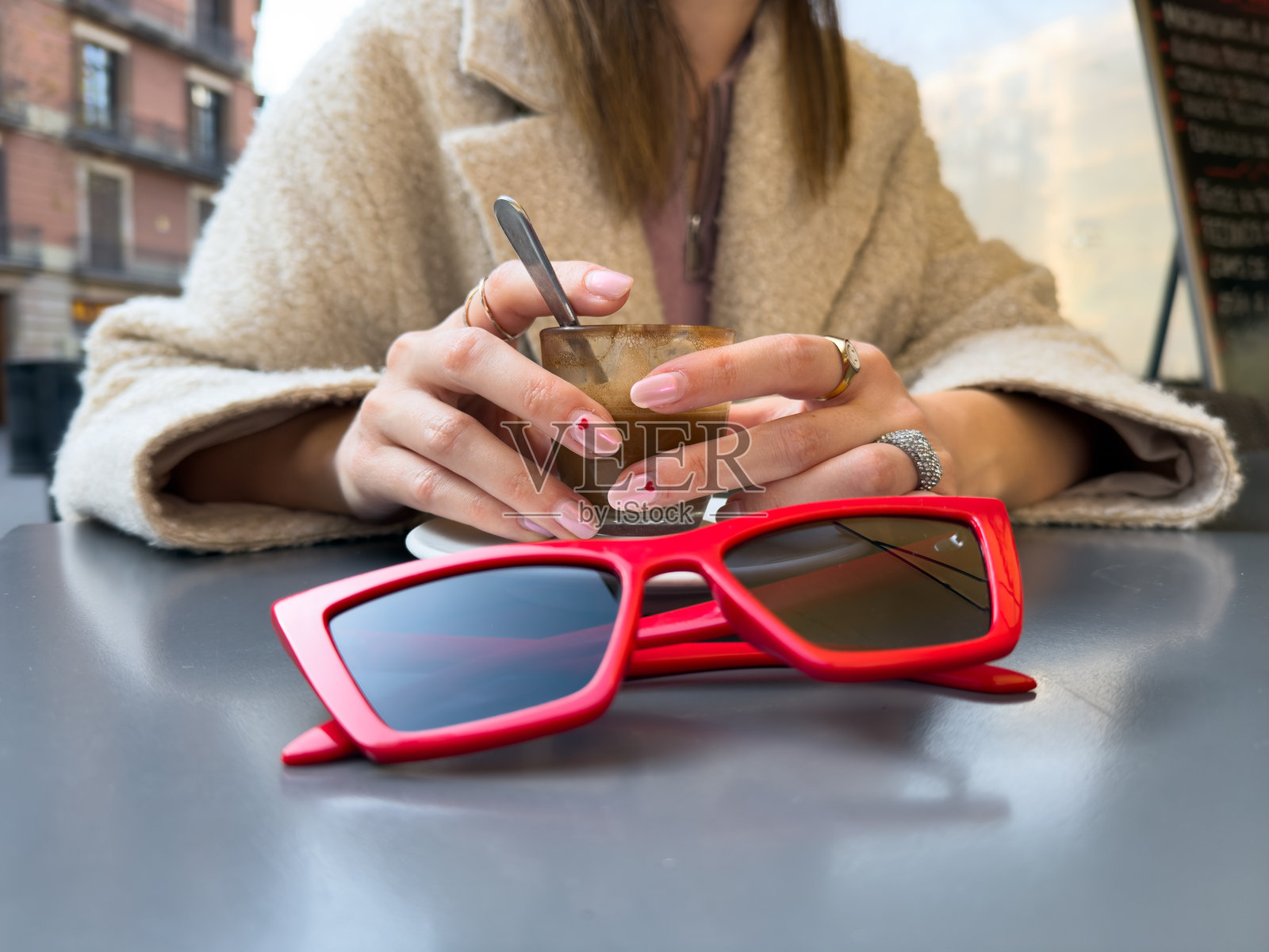 女人在户外咖啡馆享受咖啡休息，佩戴时尚的红色太阳镜。城市街头生活方式。照片摄影图片