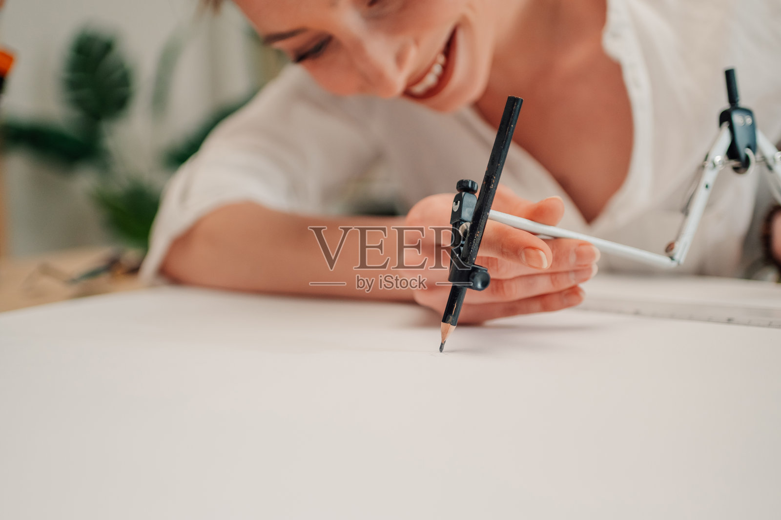 建筑师在办公室的蓝图上用圆规画圆。照片摄影图片