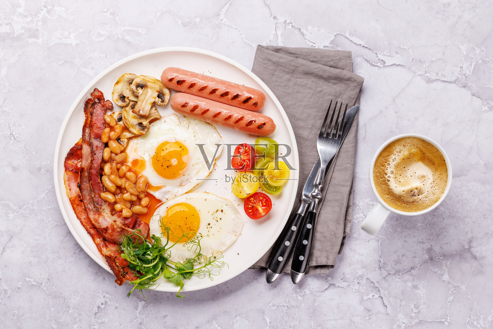 经典早餐盘，包含煎蛋、脆皮培根、香肠和新鲜番茄照片摄影图片